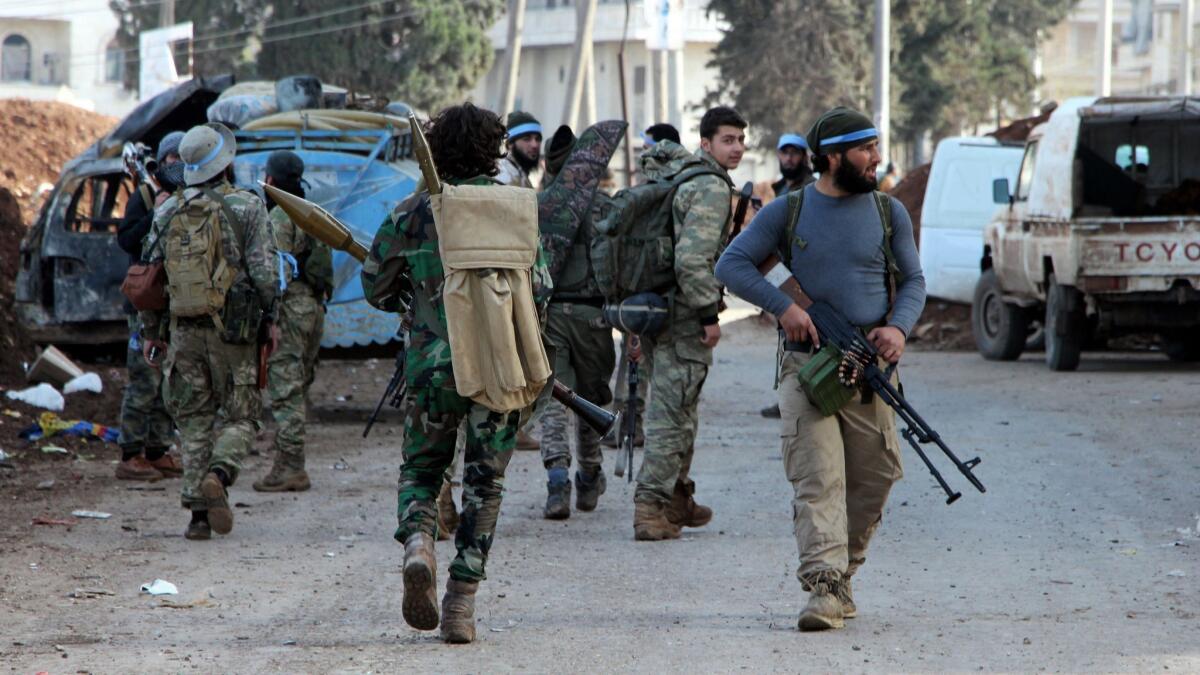 Turkish-backed Syrian opposition fighters walk in the city of Afrin in northwestern Syria on March 18, 2018.