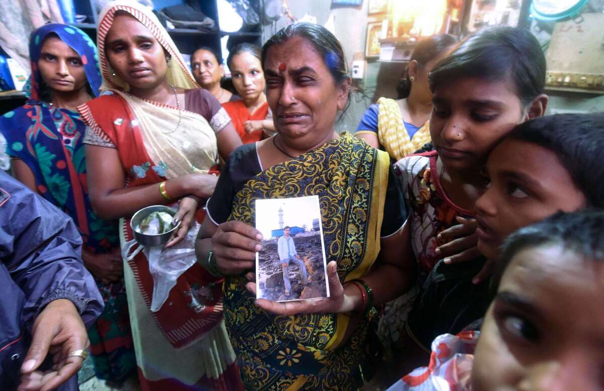 An Indian woman holds a picture of a family member who died after consuming toxic homemade liquor in the Laxmi Nagar slum near Mumbai.
