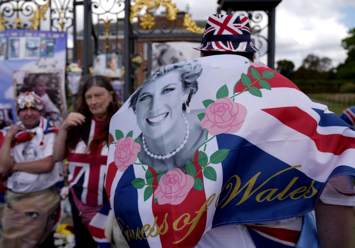 People wave a flag as they stand near a Union Jack banner depicting a smiling woman wearing a pearl necklace 
