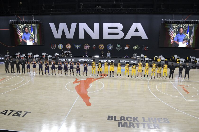 Members of the Phoenix Mercury, left, and Los Angeles Sparks stand for a moment of silence in honor of Breonna Taylor 
