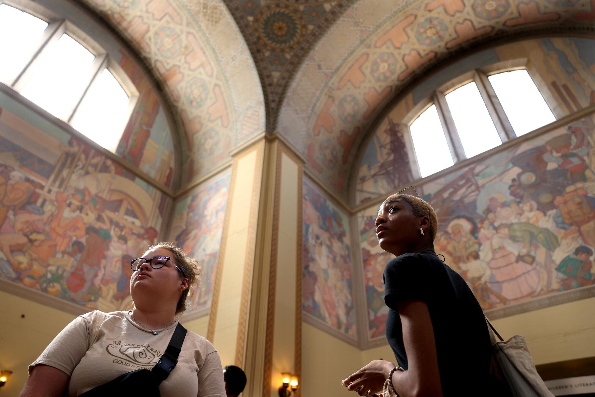 Two teen girls look at murals inside Los Angeles Central Library.