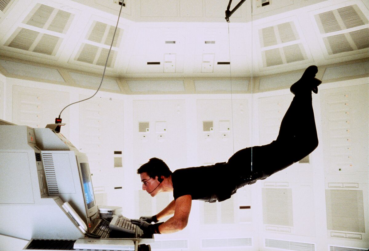 Tom Cruise hangs on a wire above a computer console