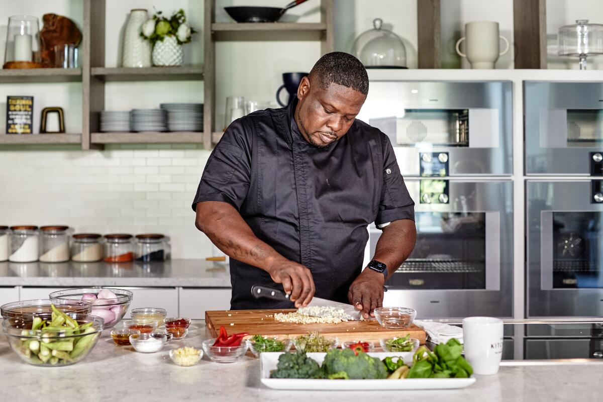 A man in a kitchen dices vegetables