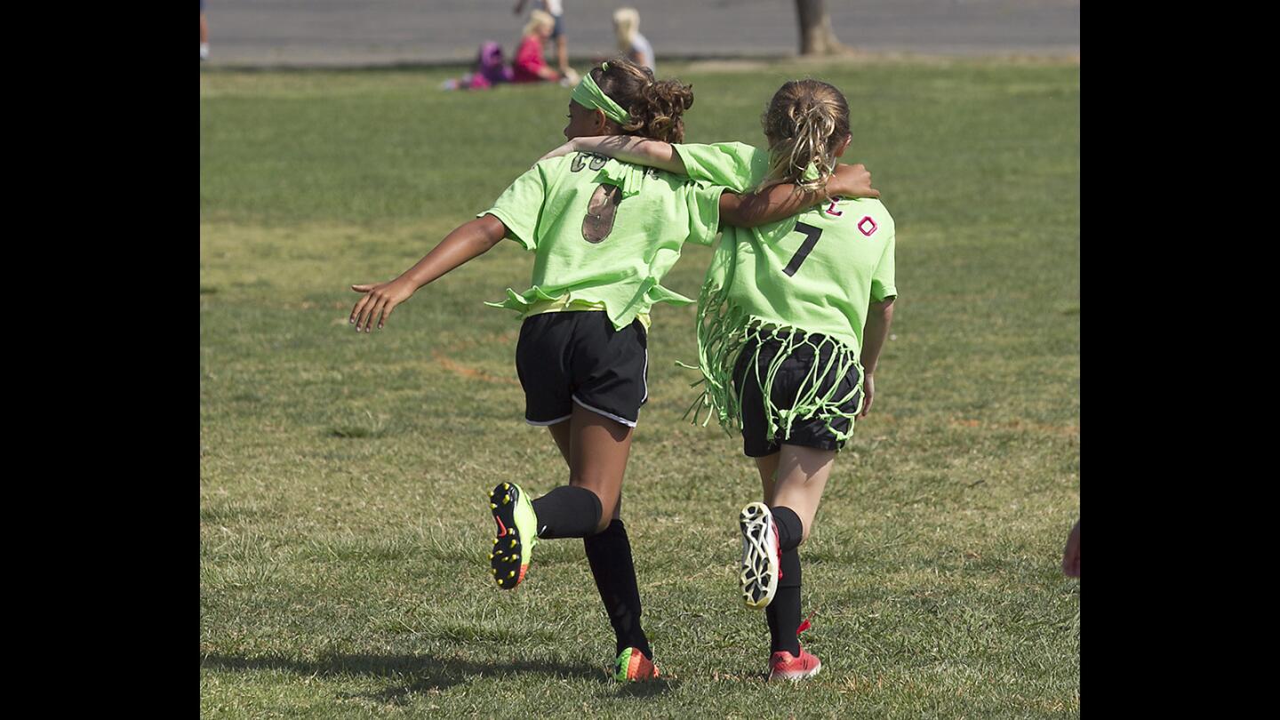 Lincoln's Makena Cook and Miley Perisi, from left, run upfield arm in arm after a goal by Cook during the Daily Pilot Cup girls' 3-4 bronze division game against Newport Heights.
