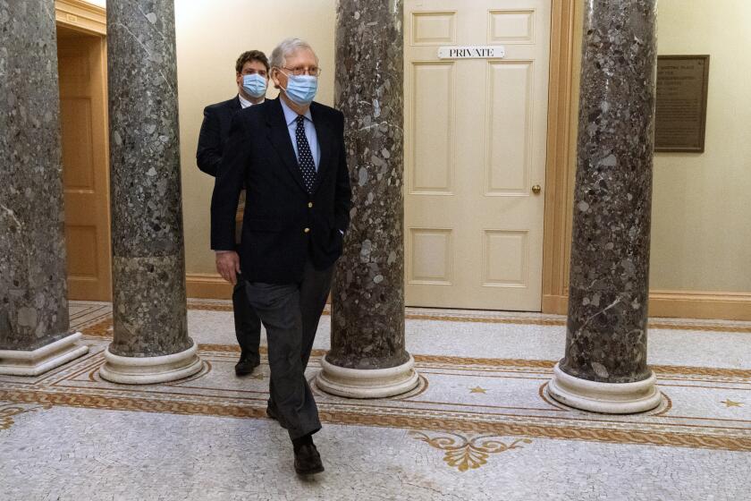 Followed by a staffer, Senate Majority Leader Mitch McConnell of Ky., right, leaves the Capitol for the day, Tuesday, Dec. 29, 2020, on Capitol Hill in Washington. (AP Photo/Jacquelyn Martin)