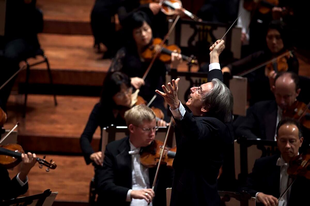 Michael Tilson Thomas with his arms up at this side looking up as he conducts and orchestra