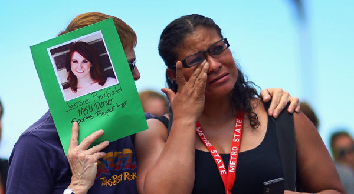 PK McKenzie, left, comforts Stella Ojeda while holding a picture of her former classmate, movie theater shooting victim Jessica Ghawi, during a vigil in Denver.