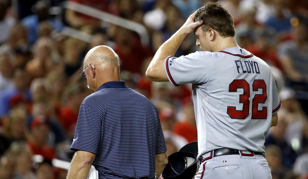 Braves starting pitcher Gavin Floyd walks off the field with Braves trainer Jeff Porter after injuring his elbow in the seventh inning of a game against the Washington Nationals on Thursday.