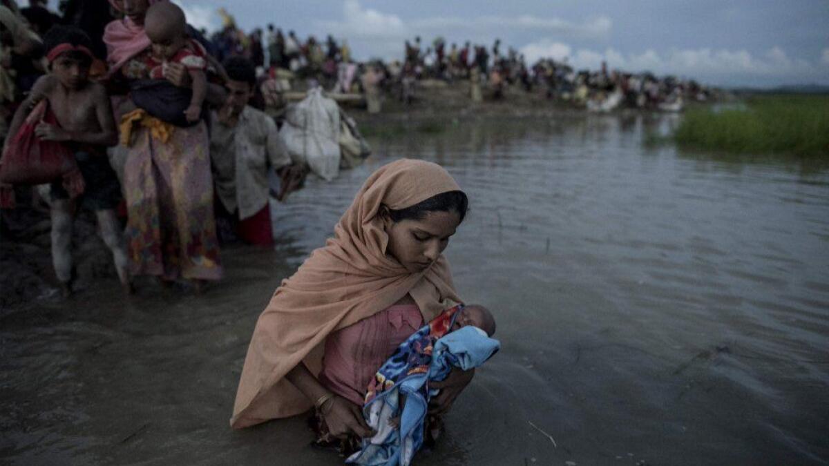 Rohingya refugees carrying children cross the Naf river from Myanmar into Bangladesh in October 2017.