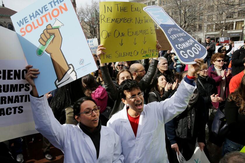 Neuroscientist Shruti Muralidhar, front left, and microbiologist Abhishek Chari, front right, hold placards and chant during a demonstration by members of the scientific community, environmental advocates, and supporters, Sunday, Feb. 19, 2017, in Boston. The scientists at the event said they want President Donald Trump's administration to recognize evidence of climate change and take action on various environmental issues. (AP Photo/Steven Senne)