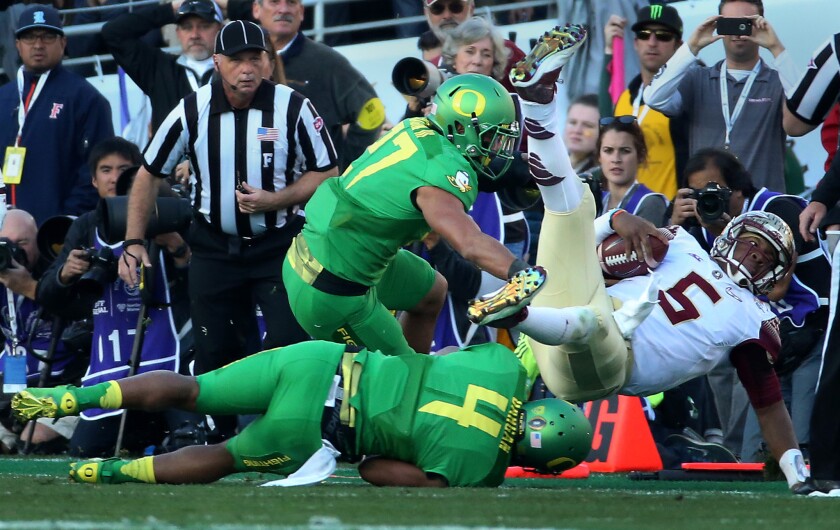 Florida State quarterback Jameis Winston is knocked out of bounds by Oregon defensive back Erick Dargan (4) and linebacker Johnny Ragin III in the first half.