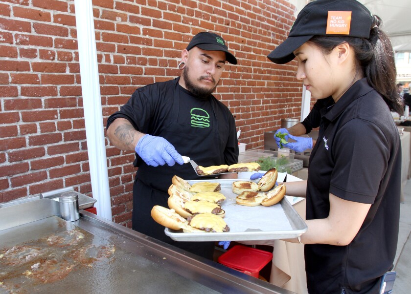 Shake Shack pro griller Mike Cosenza, left, and West Hollywood store manager Debbie Gan prepare sample burgers at an event announcing five new restaurants opening soon at Brand and Colorado in Glendale on Thursday, May 12, 2016.