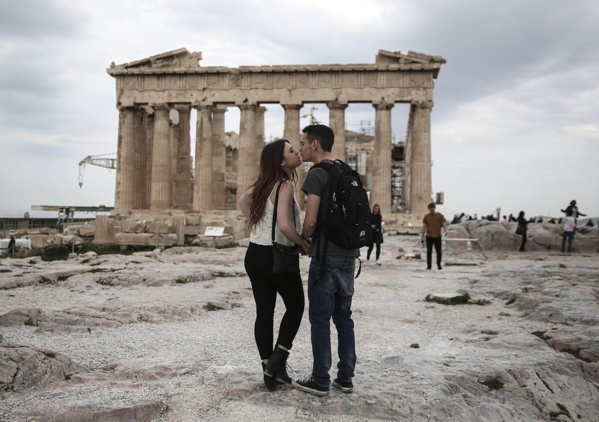 U.S. visitors Zach Branch,19, right, and Madison Franklin, 18, both from California, kiss in front of the Parthenon during their visit at the Acropolis hill in Athens, on Wednesday, April 15, 2015. Vacations in Europe have a new attraction: the euro's steep drop in value is making the continent cheaper for tourists from across the world, especially the United States and China. Branch said that as a U.S. citizen is much cheaper to travel to Europe now, than it was two years ago. (AP Photo/Yorgos Karahalis)