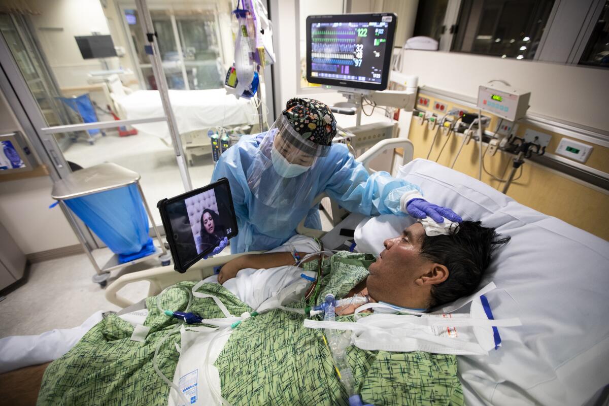 Kat Yi holds an iPad up to Eduardo Rojas, 50, inside the ICU 