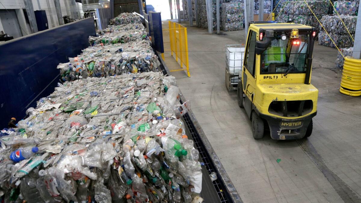 Used plastic bottles sit on a conveyor belt to be processed for recycling in Reidsville, N.C.