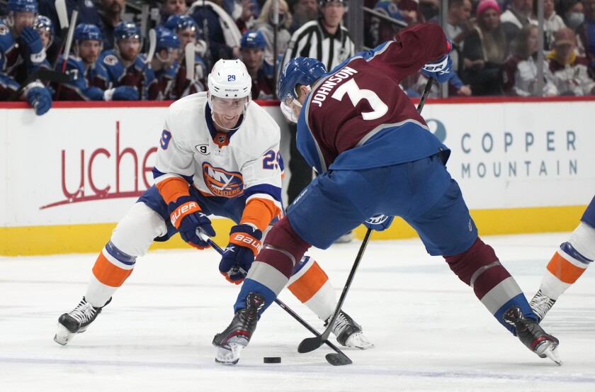 New York Islanders center Brock Nelson, left, and Colorado Avalanche defenseman Jack Johnson try to get control of the puck during the second period of an NHL hockey game Tuesday, March 1, 2022, in Denver. (AP Photo/David Zalubowski)