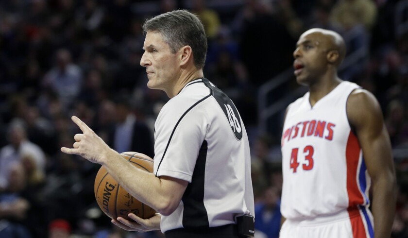 NBA referee Scott Foster, standing next to Detroit Pistons forward Anthony Tolliver, signals during a game on Friday.