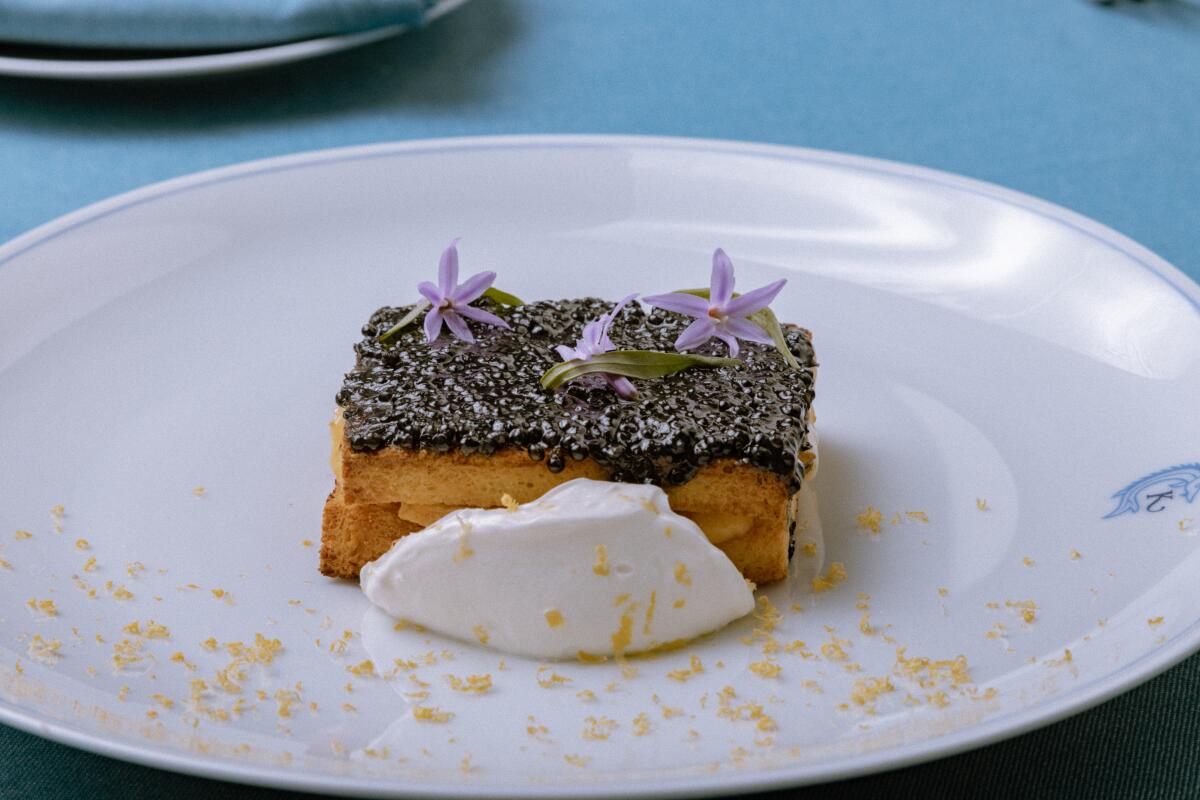 a grilled cheese topped with caviar with purple flowers on top