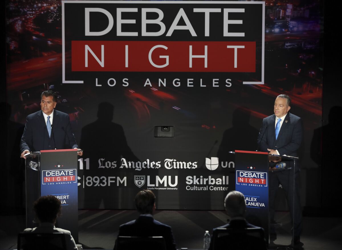 Two men stand at podiums on a stage. Behind them reads "Debate night Los Angeles"