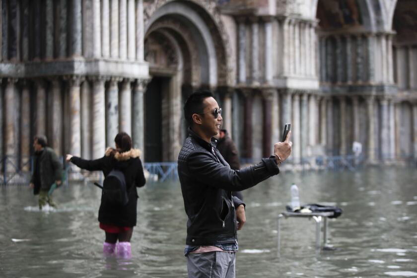 Tourists take pictures in a flooded St. Mark's Square, in Venice, Wednesday, Nov. 13, 2019. The high-water mark hit 187 centimeters (74 inches) late Tuesday, meaning more than 85% of the city was flooded. The highest level ever recorded was 194 centimeters (76 inches) during infamous flooding in 1966. (AP Photo/Luca Bruno)