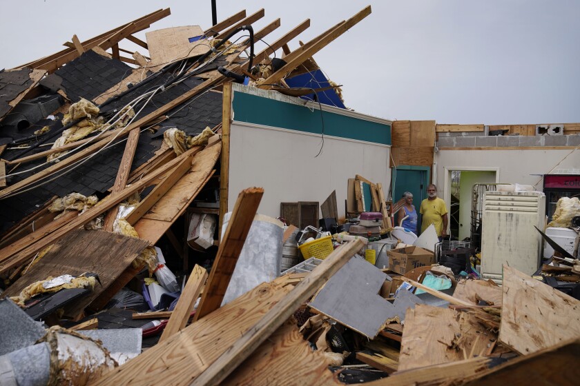 Two adults stand amid the rubble of their business building destroyed by Hurricane Ida 