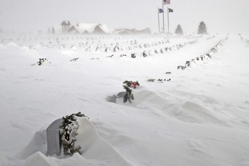 Rows of headstones at the North Dakota Veterans Cemetery are blanketed by drifting snow Thursday, Dec. 22, 2022, in Mandan, N.D. (Tom Stromme/The Bismarck Tribune via AP)
