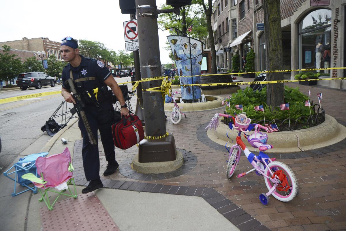 A police officer walks past chairs and a bicycle left along a parade route after the mass shooting in Highland Park, Ill.