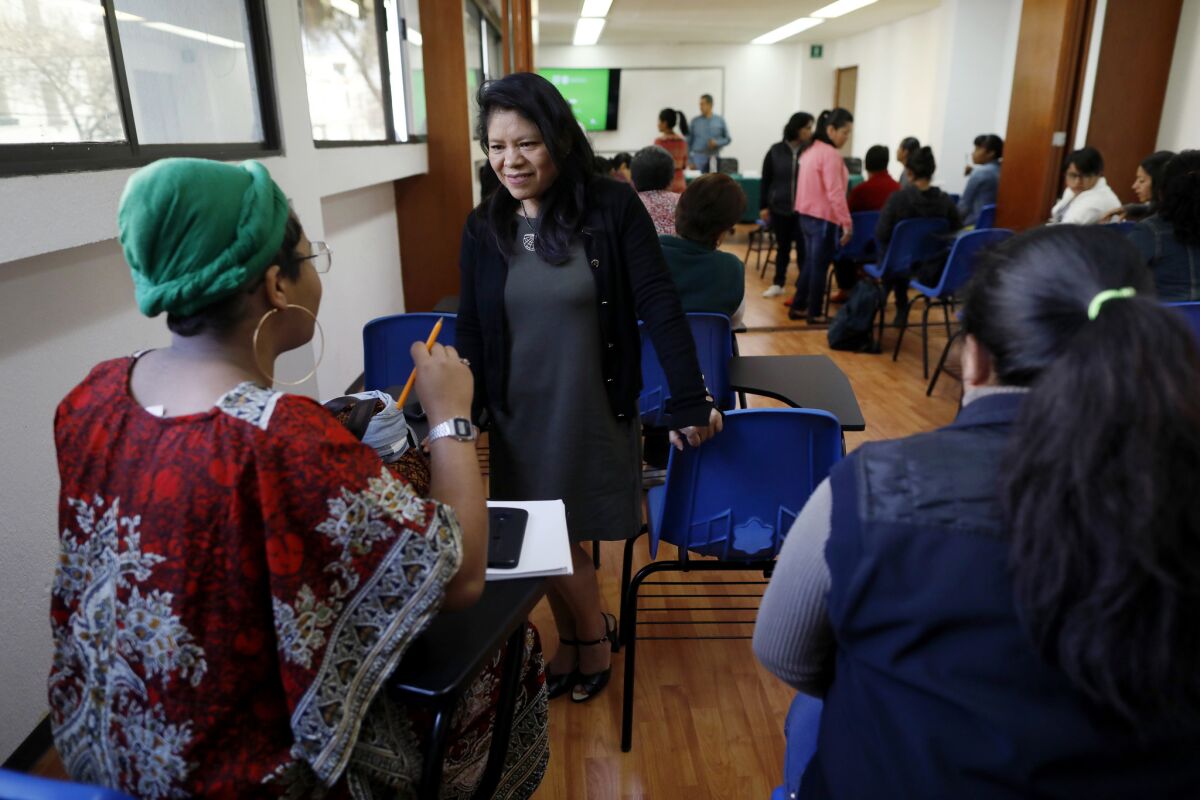 Marcelina Bautista, general director of the Center for Support and Training of Household Employees, center, visits with attendees before speaking at a labor rights conference for domestic workers in Mexico City in February.
