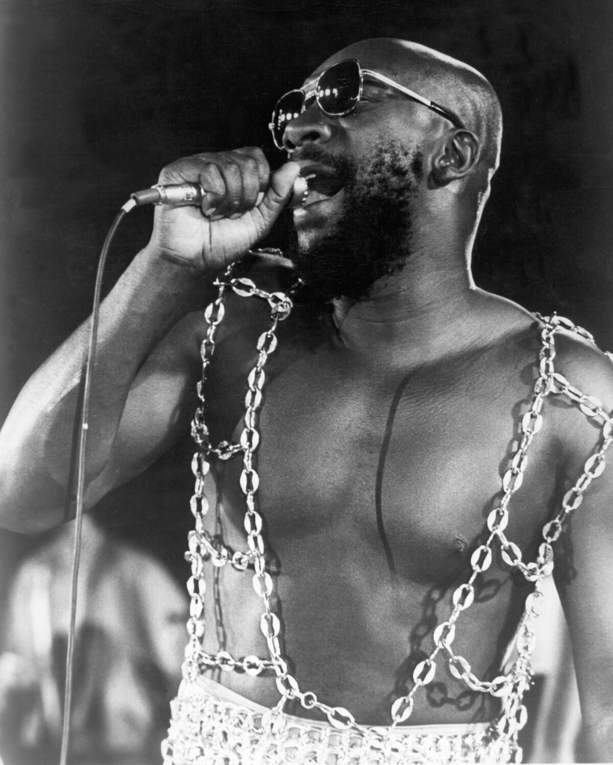 A Black singer performs onstage wearing chains for a shirt