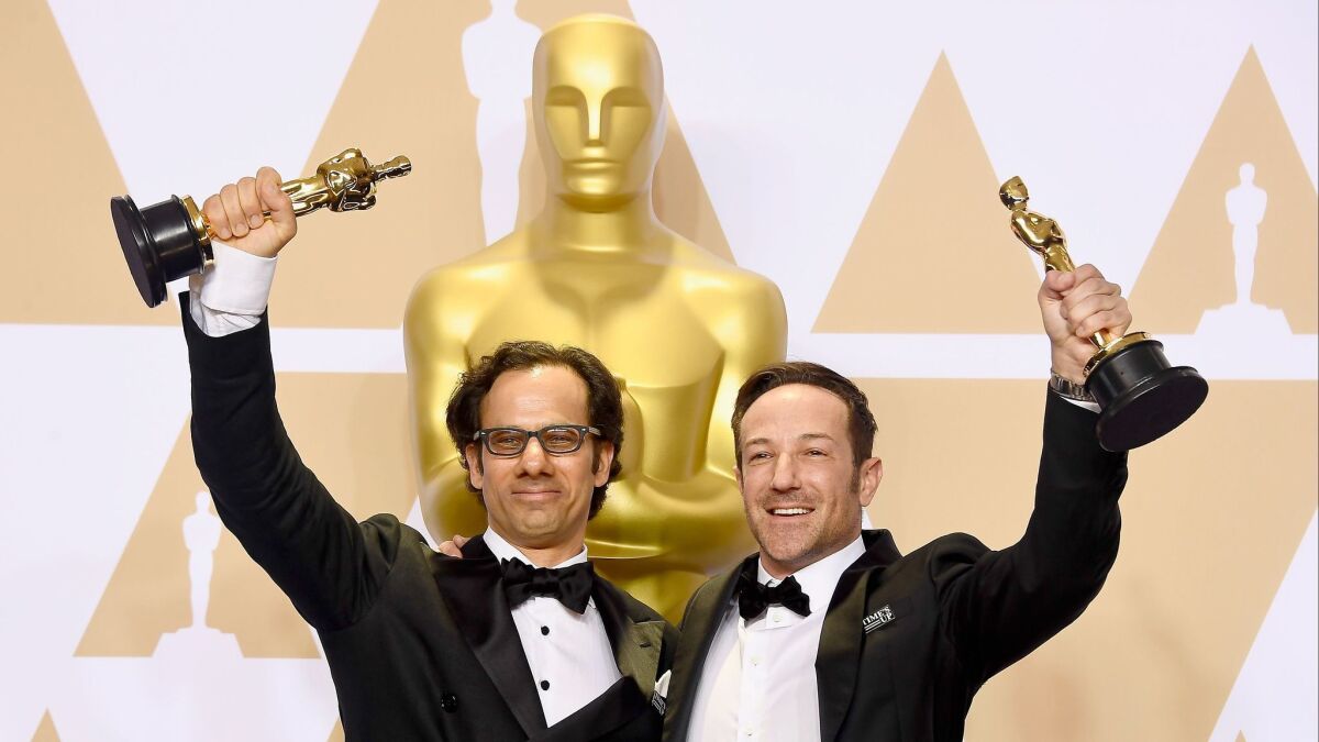 Producer Dan Cogan, left, and director Bryan Fogel, winners of the documentary feature award for "Icarus," pose in the press room at the 90th Academy Awards.