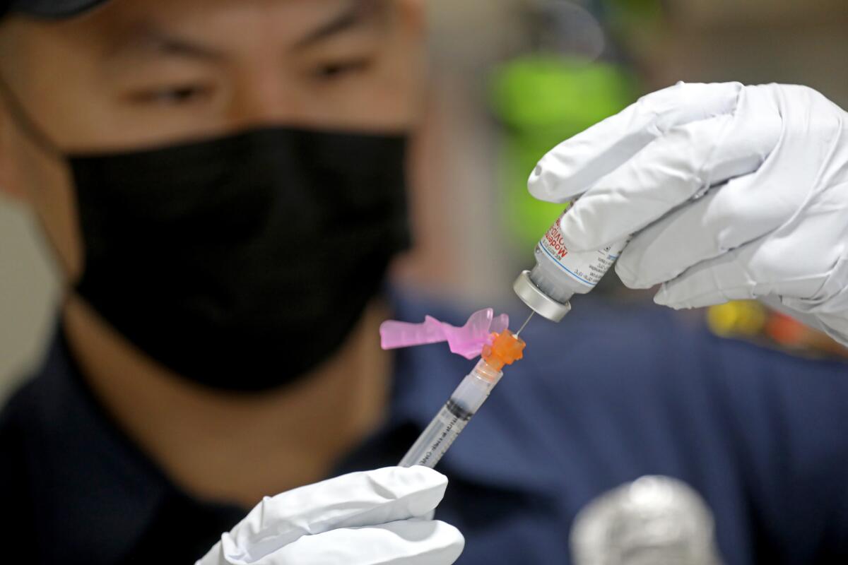 A firefighter paramedic prepares a Moderna COVID-19 shot.