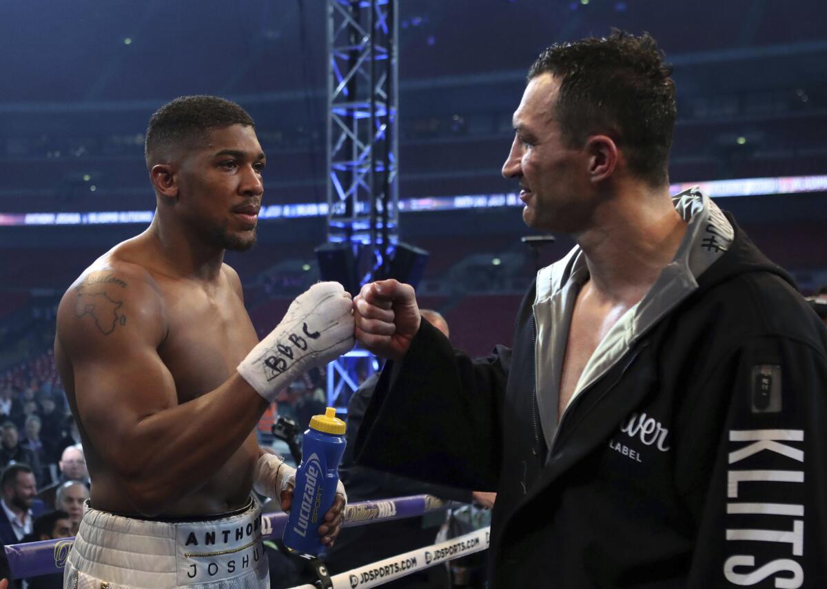 Anthony Joshua and Wladimir Klitschko bump fists after their first heavyweight championship bout, which Joshua won by technical knockout.