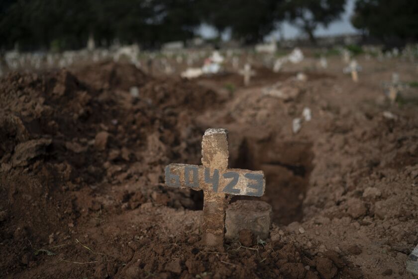 A cross marks the grave of 57-year-old Paulo Jose da Silva, who died from the new coronavirus, in Rio de Janeiro, Brazil, Friday, June 5, 2020. According to Monique dos Santos, her stepfather mocked the existence of the virus, didn't use a mask, didn't take care of himself, and wanted to shake hands with everybody. "He didn't believe in it and unfortunately he met this end. It's very sad, but that's the truth," she said. (AP Photo/Leo Correa)