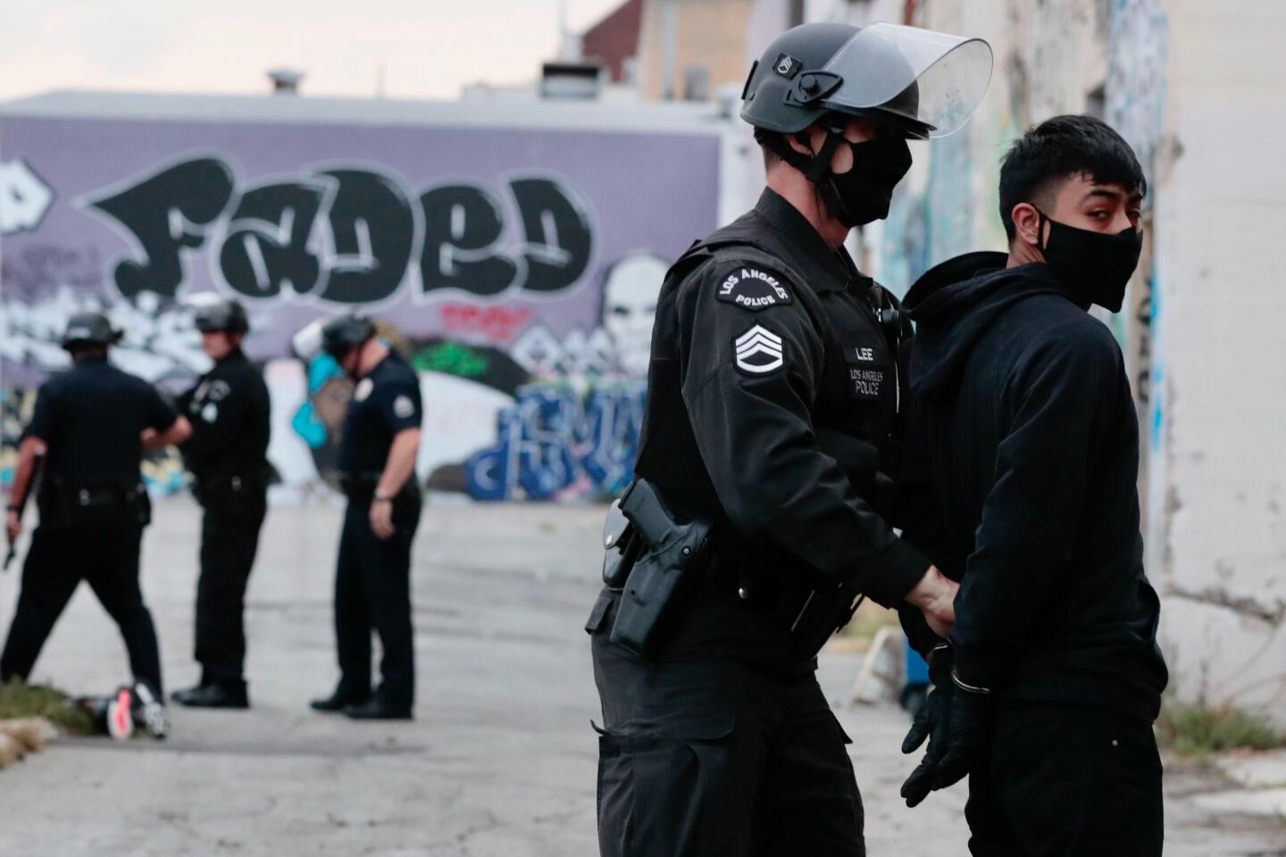 An LAPD officer arrests a suspected looter behind a Hollywood Boulevard store.