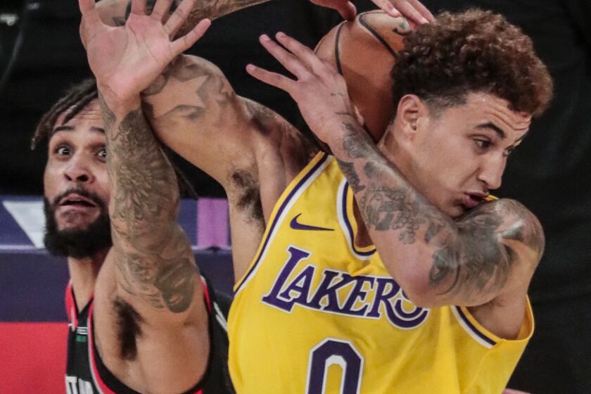Lakers forward Kyle Kuzma wrestles to control the ball while being harassed by Portland Trail Blazers guard Gary Trent Jr.