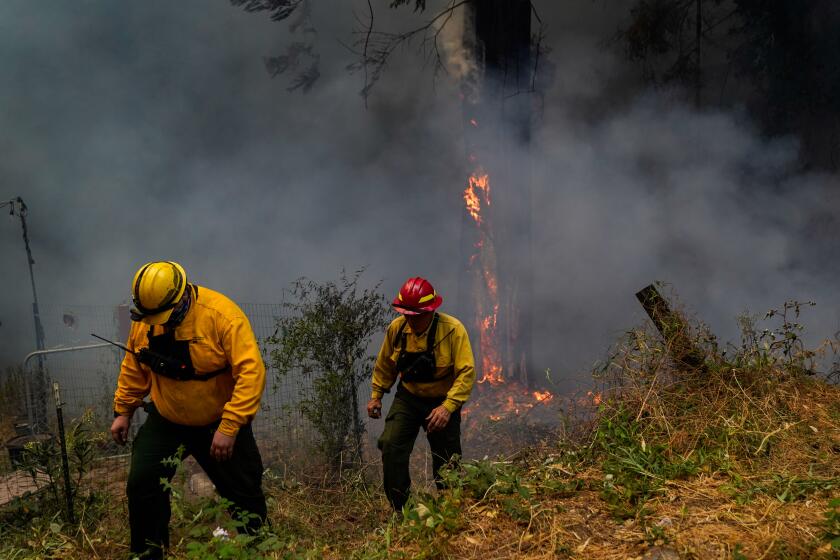 FELTON, CA - AUGUST 20: Firefighters from First Strike Engine 1 out of Eugene, Oregon inspect a fire burning near a structure along Pine Flat road during the CZU August Lightning Complex Fires on Thursday, Aug. 20, 2020 in Felton, CA. (Kent Nishimura / Los Angeles Times)