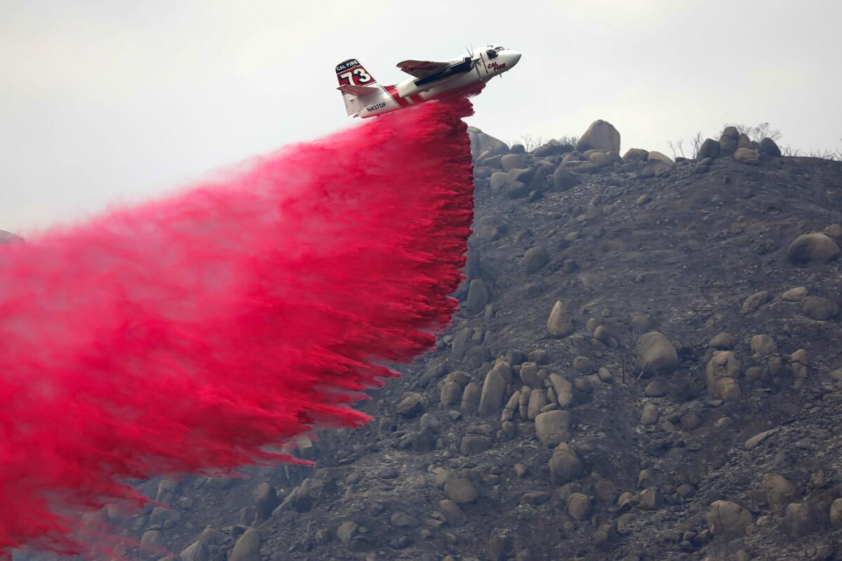 A Cal Fire plane drops Phos-Chek fire retardant on a brush fire.