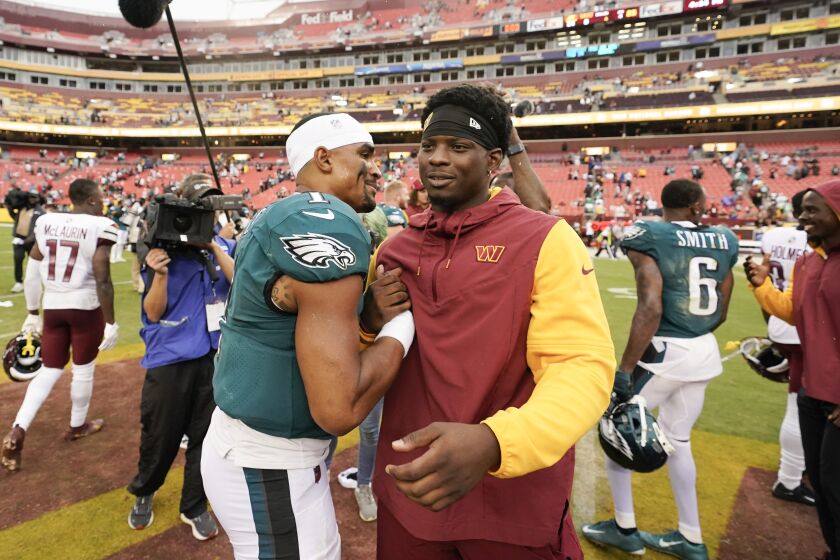 Philadelphia Eagles quarterback Jalen Hurts (1) stops to greet Washington Commanders injured running back Brian Robinson Jr., at the end of an NFL football game, Sunday, Sept. 25, 2022, in Landover, Md. Eagles won 24-8. Robinson was shot twice during an attempted carjacking in Washington on August 28th and has to miss the first 3 games of the season. (AP Photo/Alex Brandon)