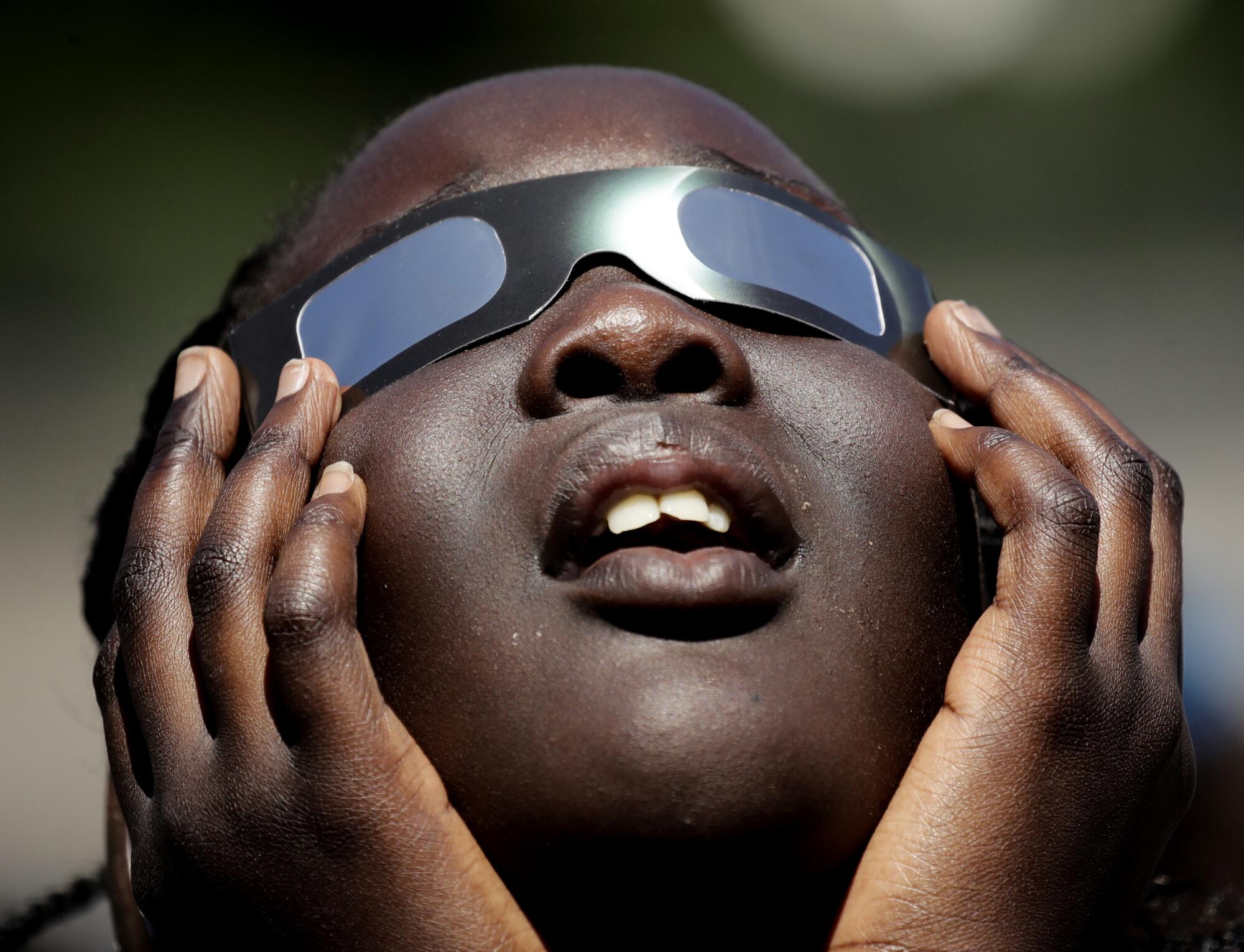 一名女孩使用特殊眼镜观看日食。