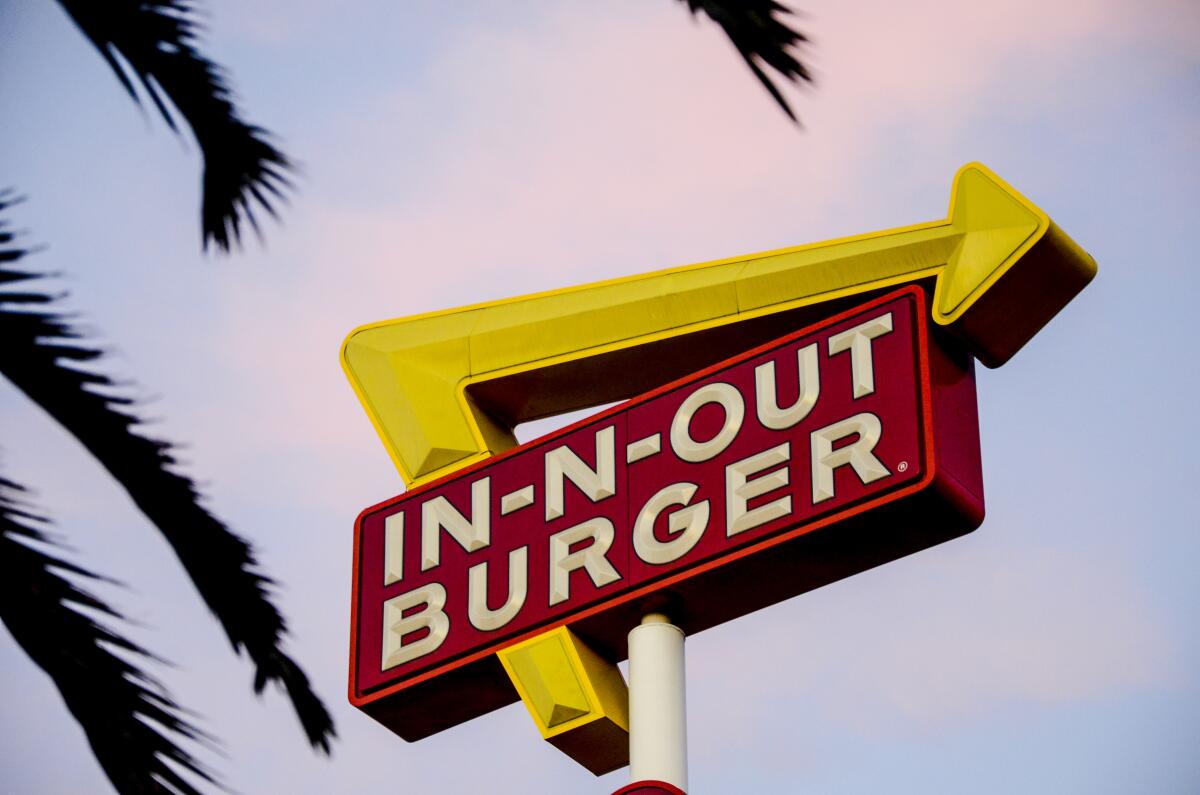 In-N-Out Burger sign framed by palm fronds.