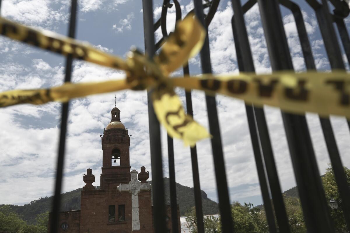 FILE - Police tape cordons off the crime scene around the church of Cerocahui, Mexico, June 22, 2022, where two elderly Jesuit priests were killed inside the church. It's been two months since the pair of Jesuit priests were killed in this remote mountain community in northern Mexico and the suspected killer remains on the loose. (AP Photo/Christian Chavez, File)