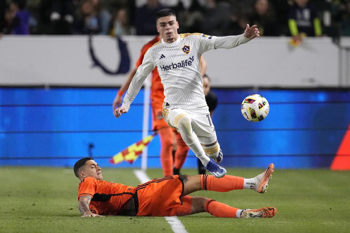 Galaxy forward Gabriel Pec jumps over Houston Dynamo defender Franco Escobar.