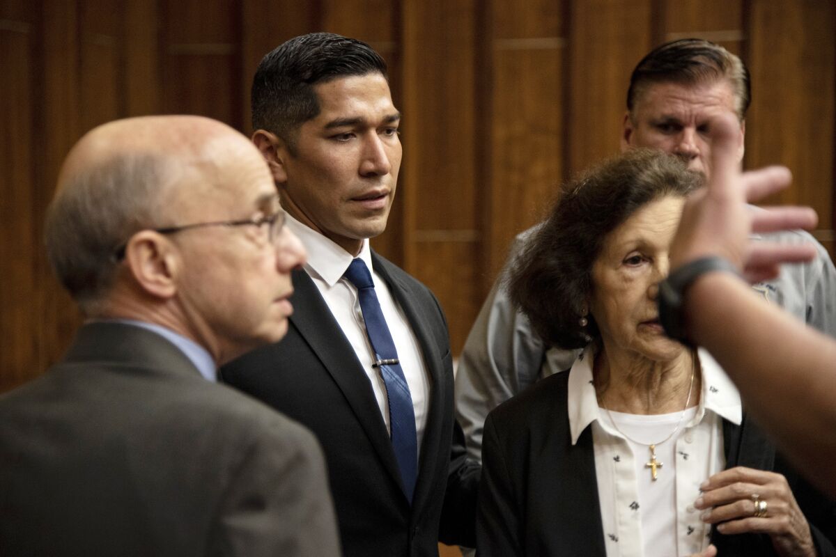 Jonathan Aledda and his parents, Martha and Mark Aledda, far right, are ushered to leave out of a backdoor in the courtroom after Judge Alan S. Fine sentenced Aledda to one year of administrative probation on July 3, 2019, in Miami. An appeals court ordered a new trial on Wednesday, Feb. 16, 2022, for Jonathan Aledda, a former Florida police officer who was sentenced to probation for shooting at a severely autistic man and wounding the man’s caretaker. (Jennifer King/Miami Herald via AP, File)