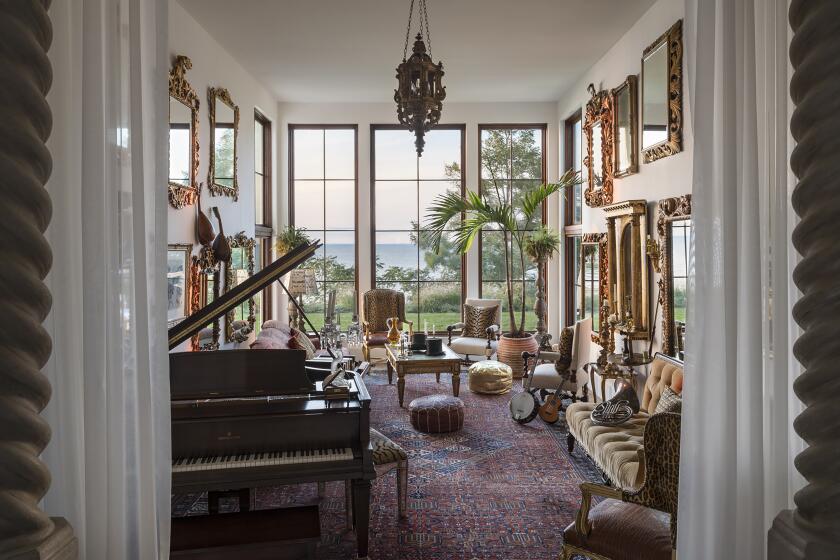 A narrow music room of a house on Long Island is opened up visually by covering facing walls with mirrors hung salon style.