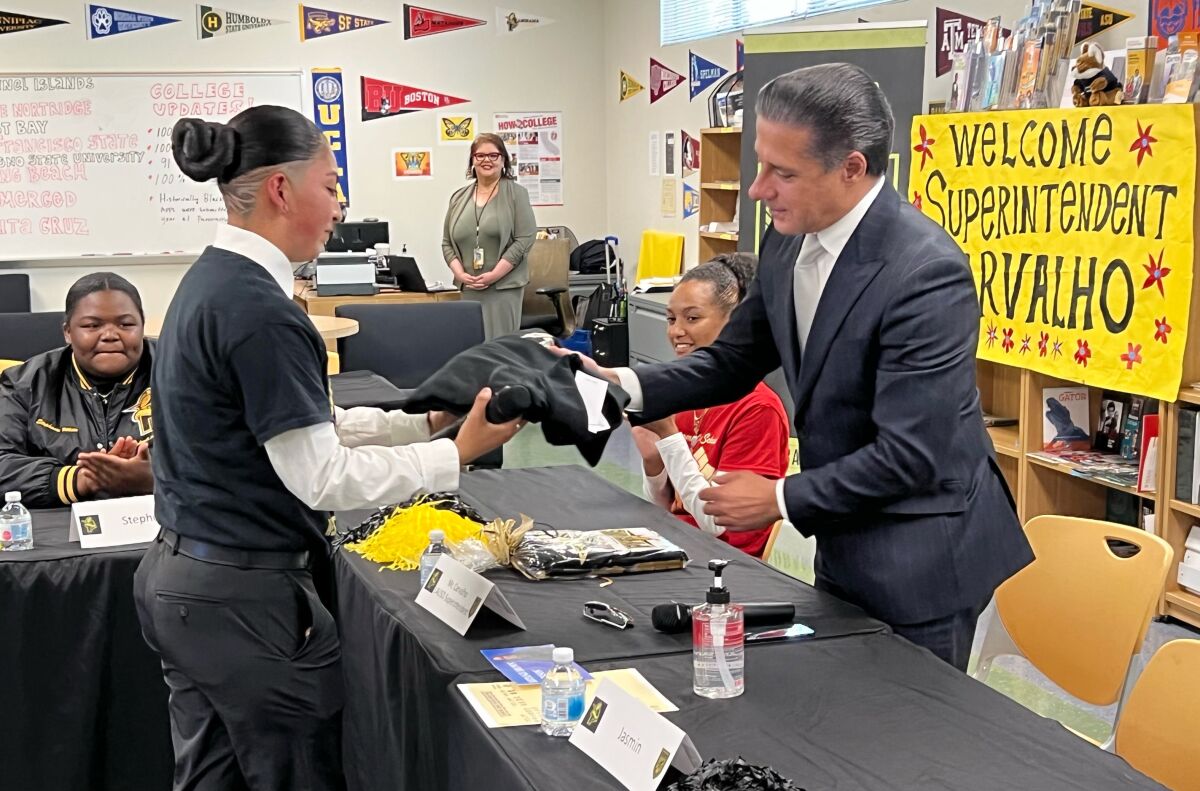 A student hands a sweatshirt to the L.A. schools superintendent.