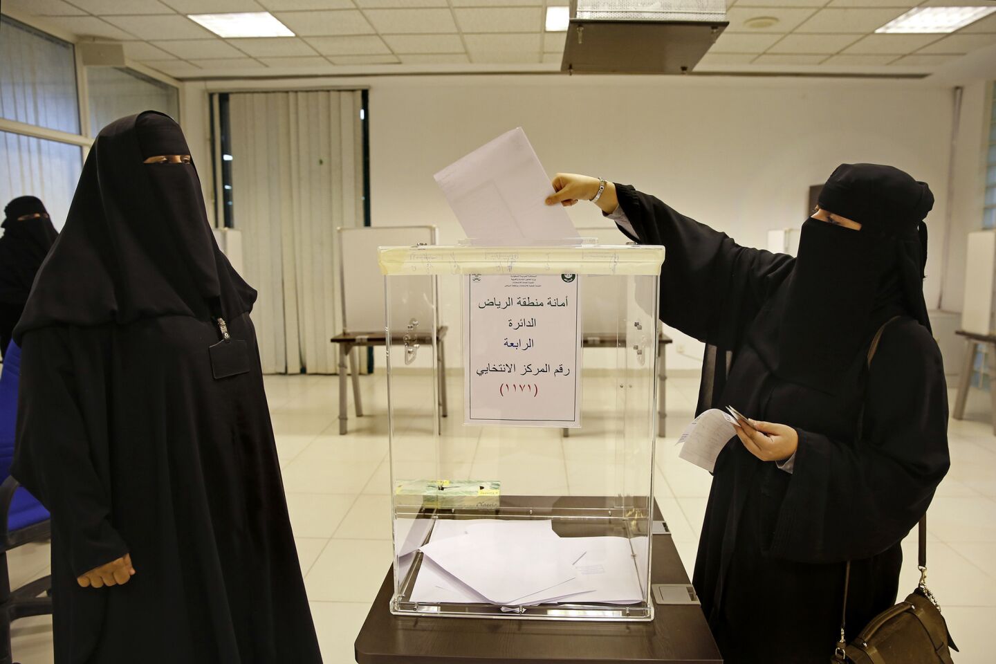 Volunteer Fatima Al-Druby, left, stands by as a 4th District voter casts her ballot.
