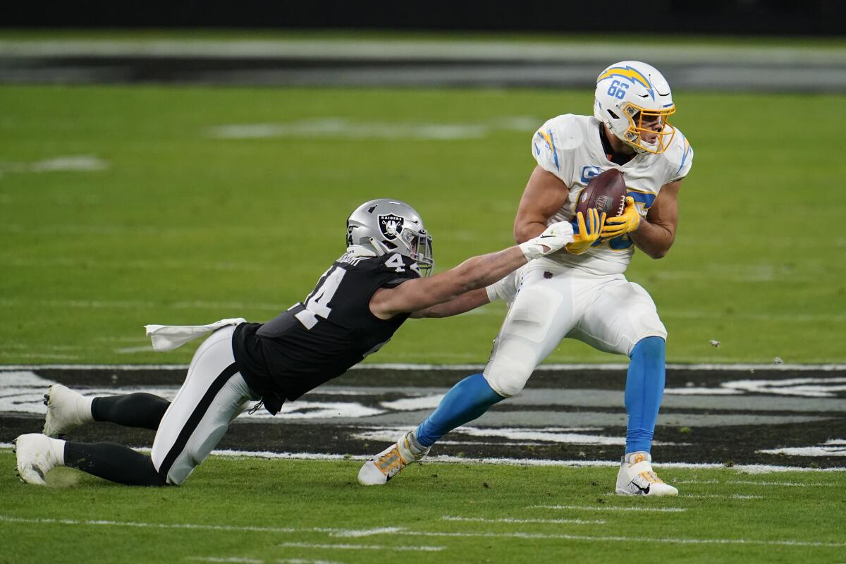 Chargers tight end Hunter Henry catches a pass as Las Vegas Raiders' Nick Kwiatkoski tries to make the tackle.