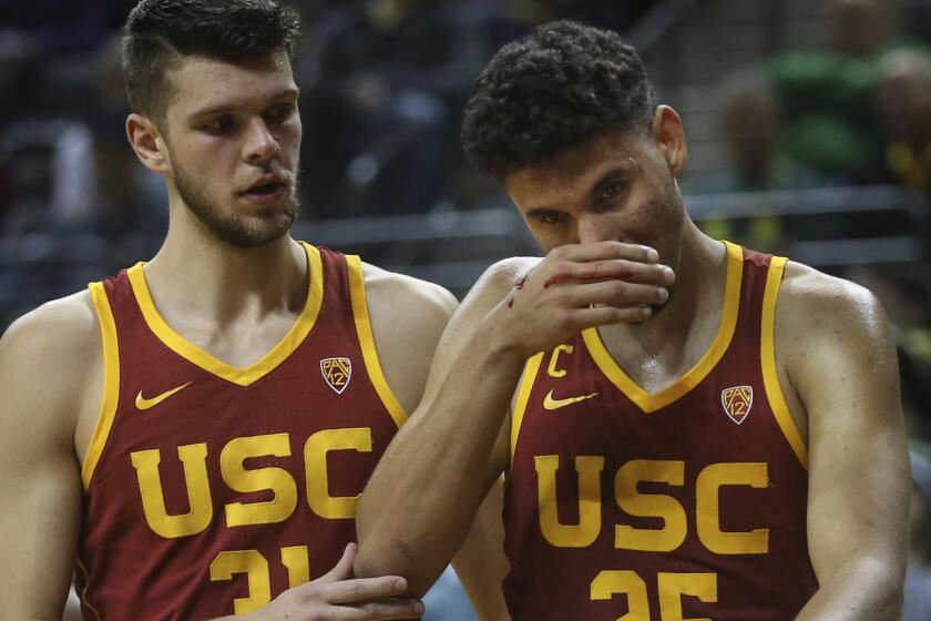 Southern California's Nick Rakocevic, left, helps teammate Bennie Boatwright off the floor after his nose was bloodied on a play against Oregon in the second half of an NCAA college basketball game, Sunday, Jan 13, 2019, in Eugene, Ore. (AP Photo/Chris Pietsch)