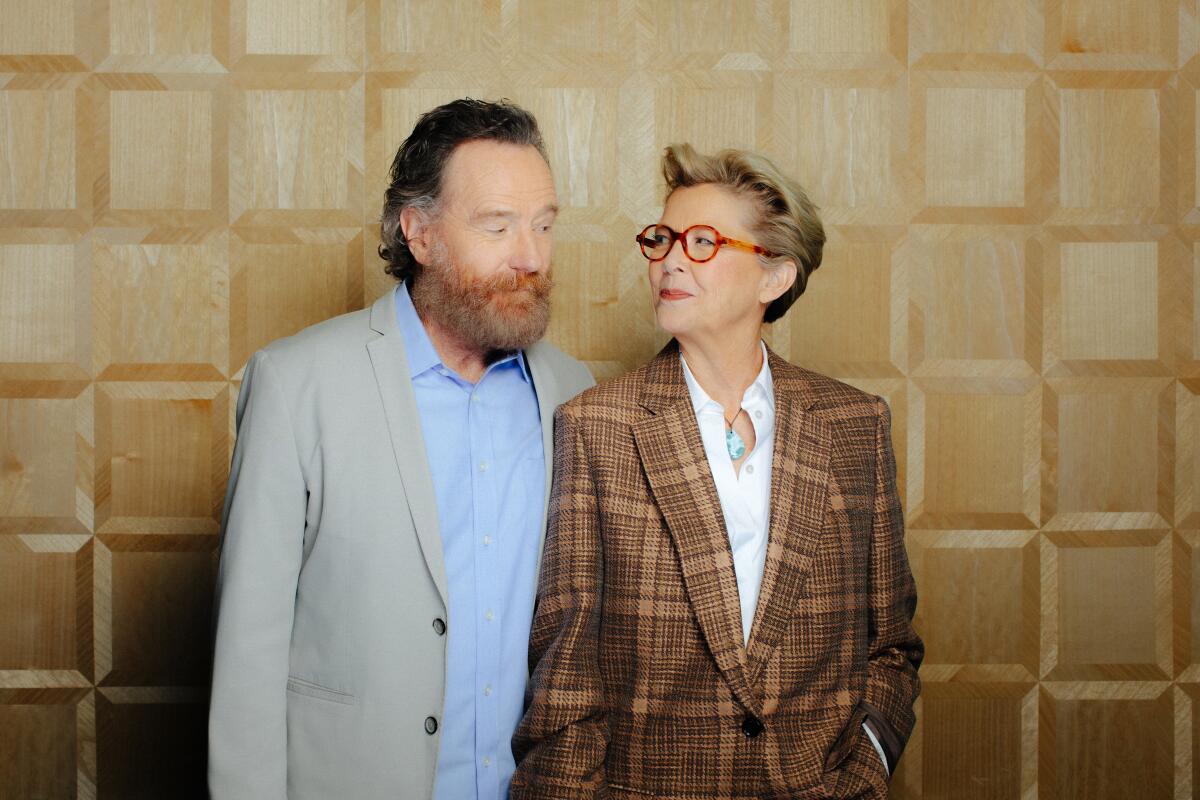 a bearded man smiling at a short-haired woman in glasses.