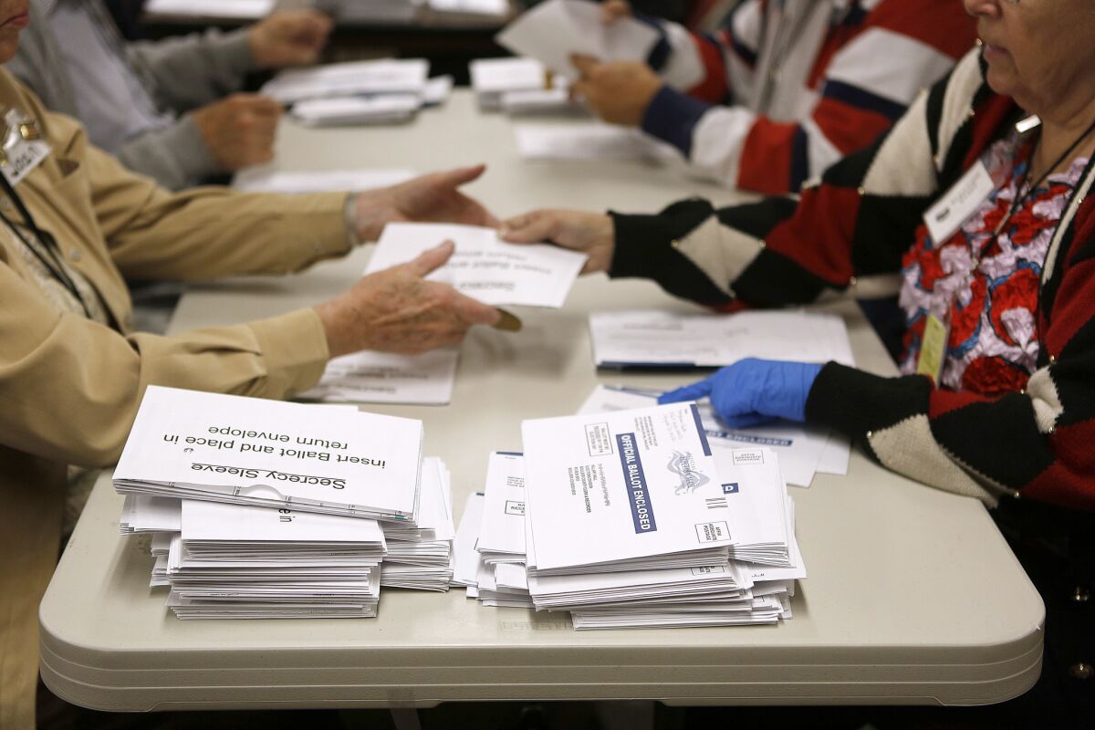 Election workers in Colorado open mail-in ballots.